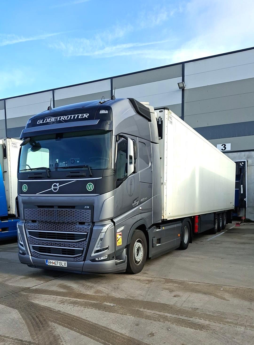 Camion Volvo FH gri poziționat la docul de încărcare al halei logistice.